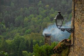 photo of a chimney and a street lamp on the background of a green mountain forest