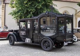 Black auto hearse with windows near the building