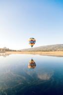 colorful hot air balloon is flying over the pond