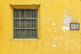 Beautiful, yellow building with the green window and sign in Cartagena, Colombia