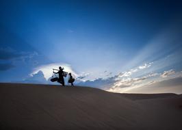 silhouettes of people on top of a sandy hill