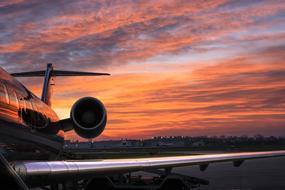 View of the side of the airplane at beautiful and colorful sunset background