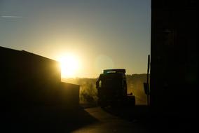 containers and truck in port are lit by the morning sun