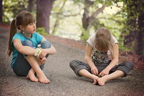 Girl children sitting on the road among the colorful plants