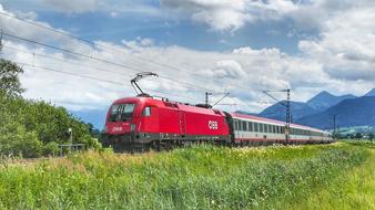 red locomotive with carriages among picturesque landscape