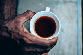 Cup with drink in dark male hand