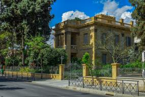 a building with green trees behind a fence
