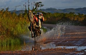 motorcyclist rides on the rear wheel through the mud