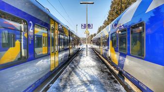 two blue trains on a railway platform