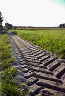 track from huge tires on the road in a green field