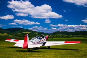 Airplane on meadow in and Clouds on Sky