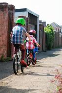 children in helmets on bicycles on the city alley