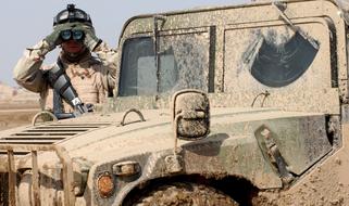 soldier with binoculars near a dirty jeep