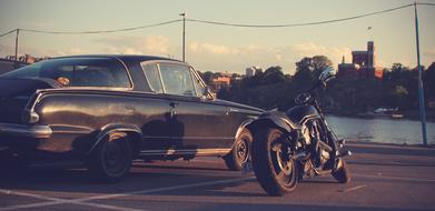 the motorcycle stands near the car on the road