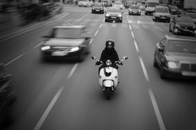 Black and white photo with the motorbike and cars on the road, in motion, in Barcelona, Spain