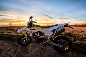 Beautiful motorcycle, near the beautiful and colorful field, among the trees, at beautiful and colorful sunset