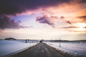 empty road beneath pink Sunset sky at Winter