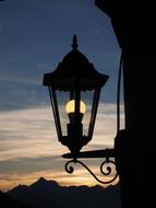 Silhouette of a lantern, with the light, at background with the mountains and beautiful sunset, in Jaufenpass, Italy