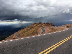 cloudy sky over a winding highway in the mountains