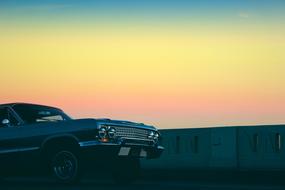 Beautiful, shiny, vintage car, at colorful, gradient sunset in the sky