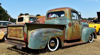 Old, colorful rusty rat rod truck, among the other colorful cars