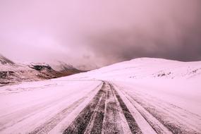 Beautiful landscape of the snowy road on the mountains in Iceland, in the winter, in pink colors