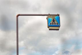 road sign pedestrian crossing on high pillar against cloudy sky background