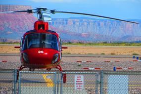 Shiny, red helicopter, among the colorful and beautiful fields and mountains