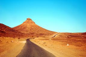 Beautiful and colorful landscape of the desert with the road, at beautiful, blue, gradient sky on background, in Morocco, Africa