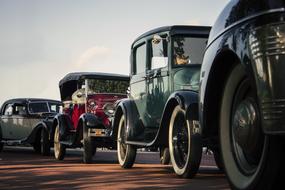 Row of the beautiful, shiny, colorful, vintage cars, on the road, in light