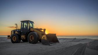 tractor on a sandy beach at dusk