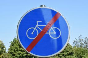 "Bikes prohibited" blue, red and white road sign near the trees