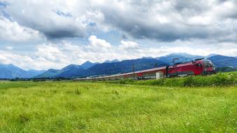 train on the railroad near fields with green grass