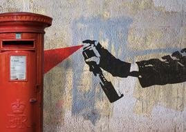 red mailbox and hand with spray graffiti