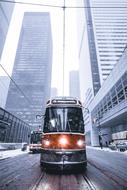 Colorful and beautiful tram, among the snowy city with the buildings, in winter