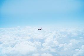 Airplane flying, above the beautiful, white clouds in the blue sky