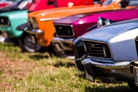 Row of the beautiful and colorful, shiny, vintage cars, on the green grass
