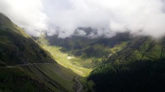 Beautiful landscape with the green valley, among the mountains in white clouds