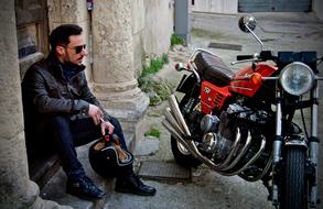 Biker in sunglasses, near the colorful Benelli 750 motorcycle
