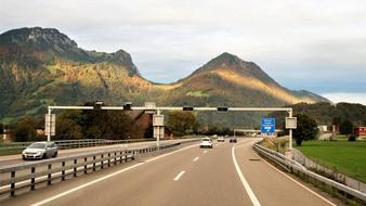 Beautiful landscape with the road with cars, near the colorful mountains