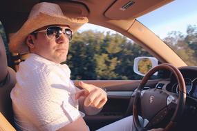 young man in a hat driving a luxury car