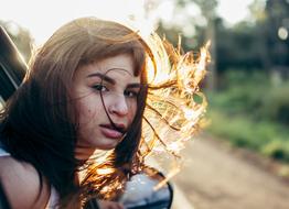 young girl with disheveled hair looking out of a car window