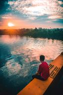 man sits on Bridge over River at sunset, indonesia, pontianak