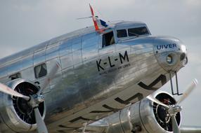 Shiny, metallic plane of KLM with the Dutch flag, under the cloudy sky