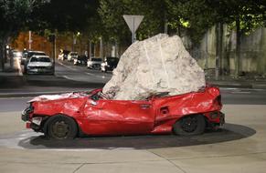 modern art white boulder on a crushed car
