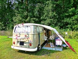 Retro, beige Volkswagen combi van, among the colorful and beautiful fields and trees