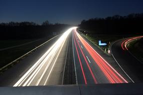 Beautiful landscape of the highway, with the colorful lights in motion, among the trees, at the night