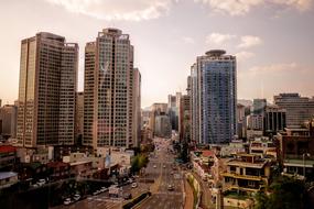 Cityscape with the colorful, shiny buildings and cars, on the road, at colorful sunset