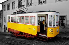 Beautiful, old, yellow, white and red train in Lisbon, Portugal, near the building