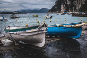 Colorful boats and ships in the beautiful port with the mountains, under the cloudy sky